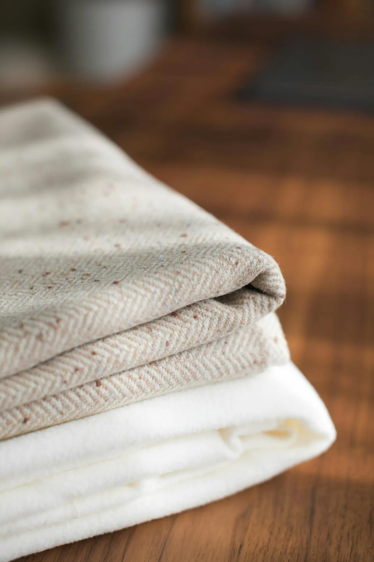 Pile de linge blanc soigneusement plié sur un plan en bois clair